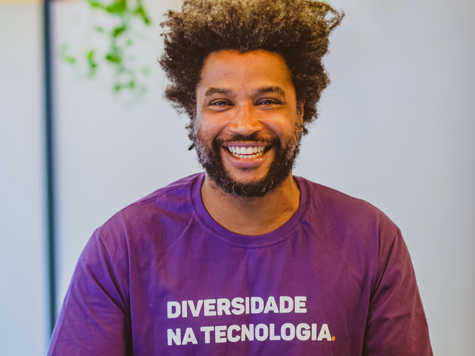 Na imagem, há um ex-aluno negro da Toti Diversidade vestindo uma camisa roxa escrito "Diversidade na Tecnologia".