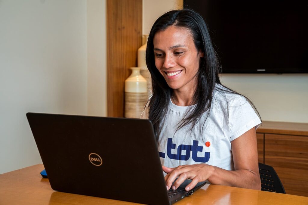 Mulher sentada mexendo em um notebook. Seu nome é Giselle Cordoné, é argentina e desenvolvedora formada pela Toti. É um dos nossos talentos de tecnologia.