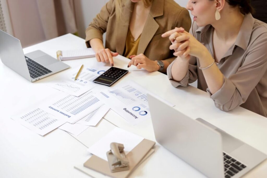 Duas pessoas sentadas a mesa, trabalhando em seus notebooks