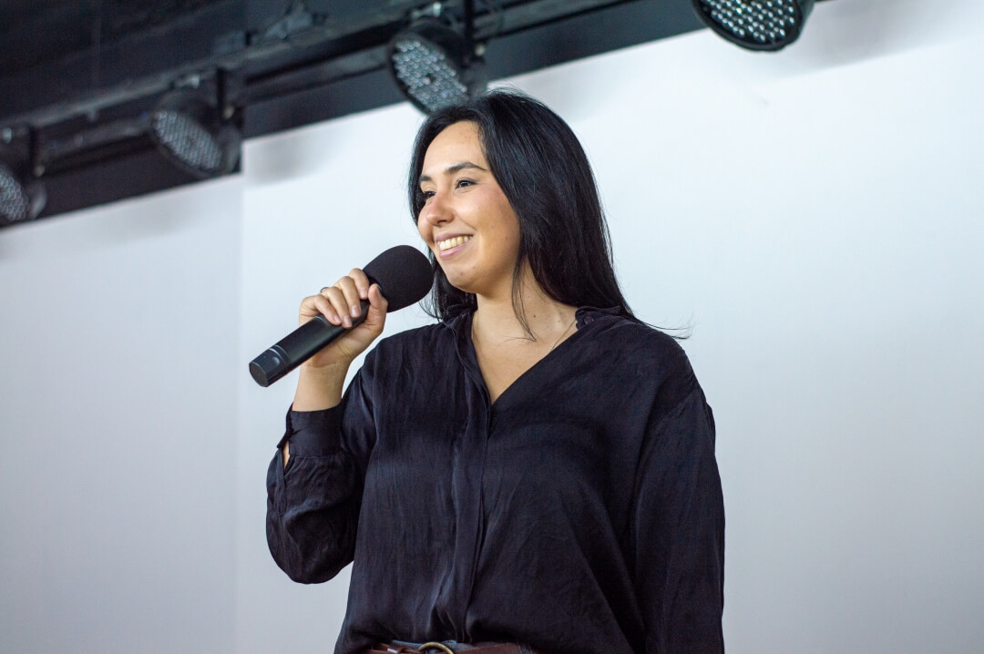 Mulher com microfone na mão palestrando.