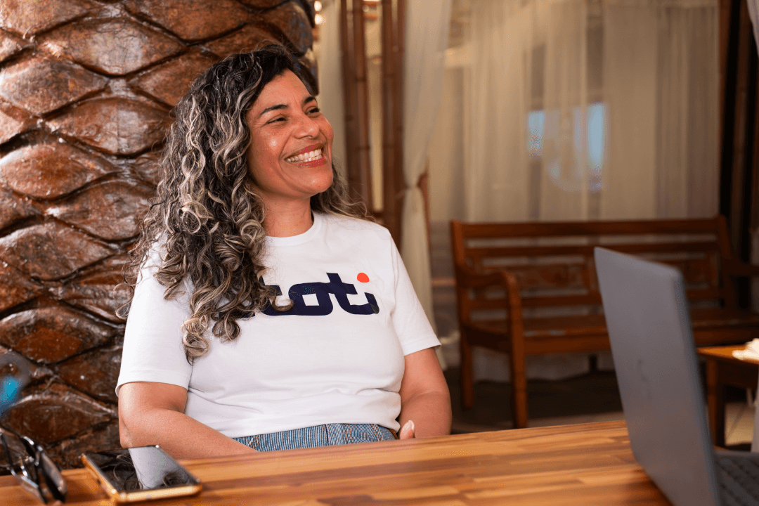 Mulher vestida com a blusa branca da TOTI sorrindo.