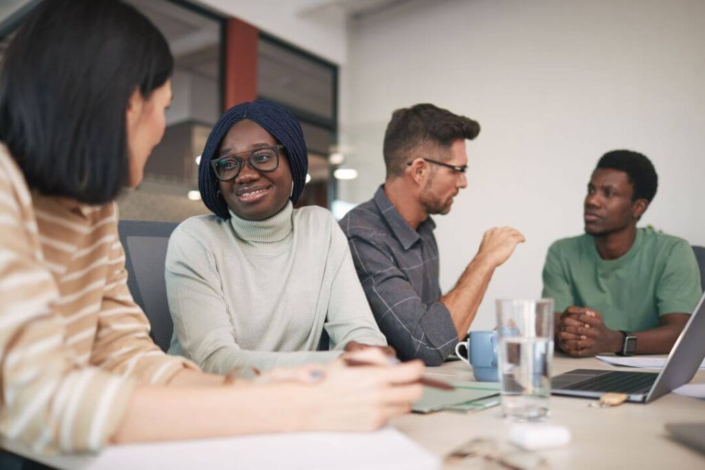 Grupo de pessoas sentadas à mesa conversando no ambiente de trabalho