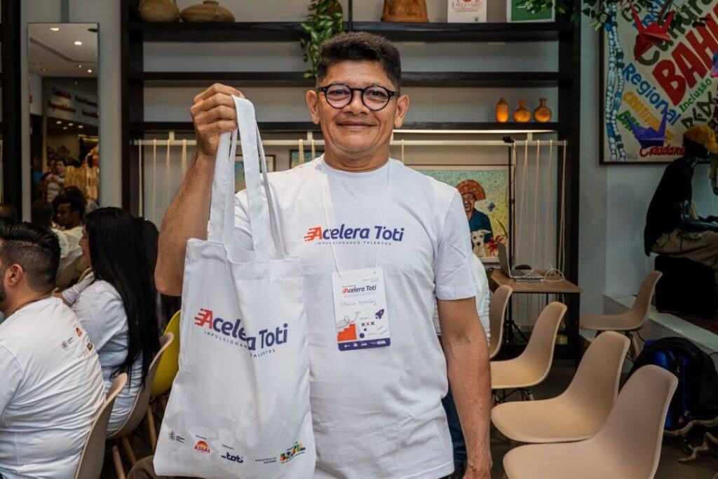 Homem com a blusa da Toti segurando uma ecobag também da Toti