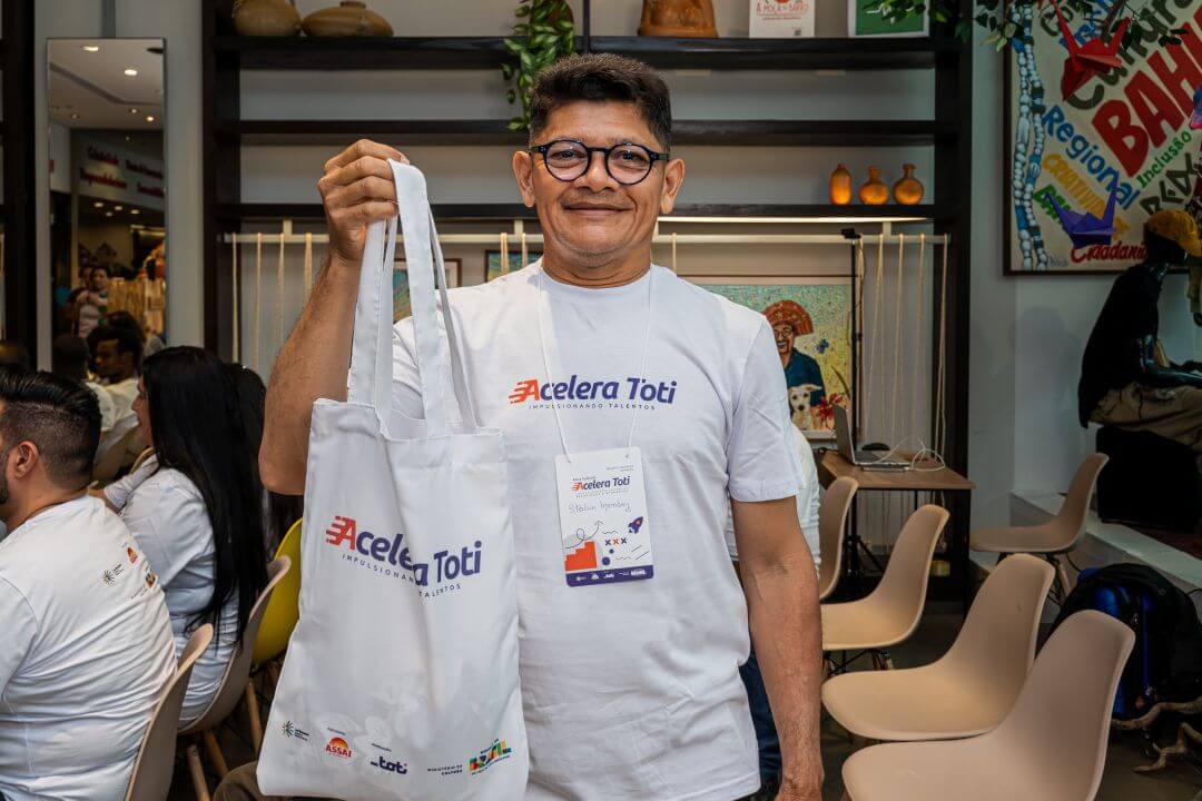Homem com a blusa da Toti segurando uma ecobag também da Toti