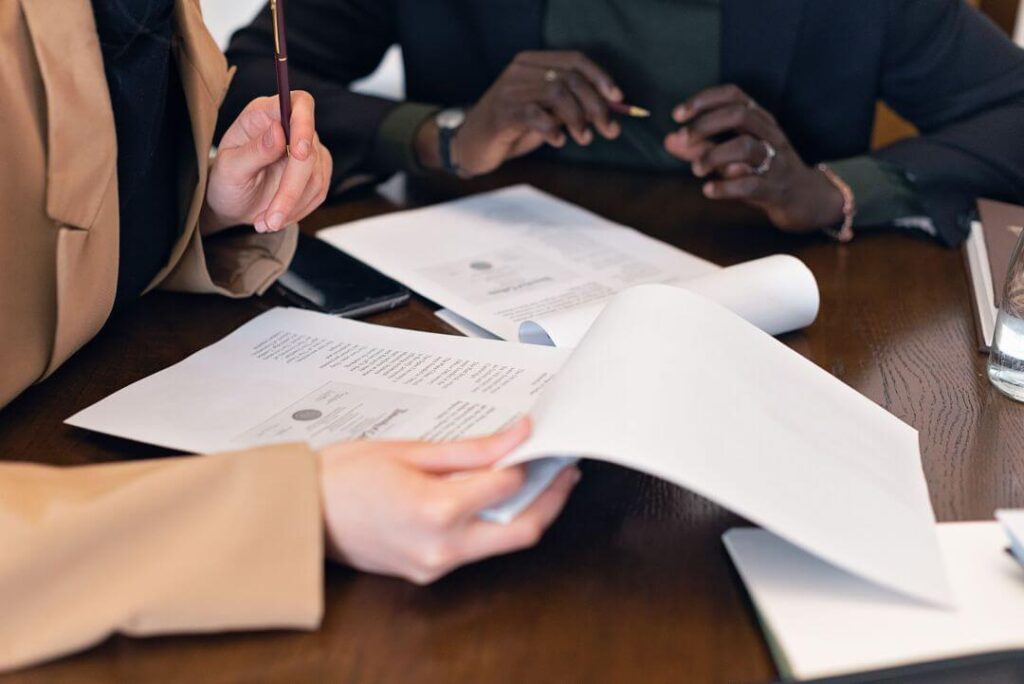 Imagem das mãos de duas pessoas segurando um documento em papel
