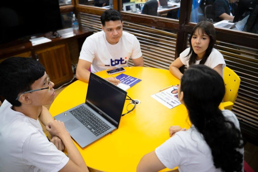 Grupo de pessoas sentadas a mesa conversando.